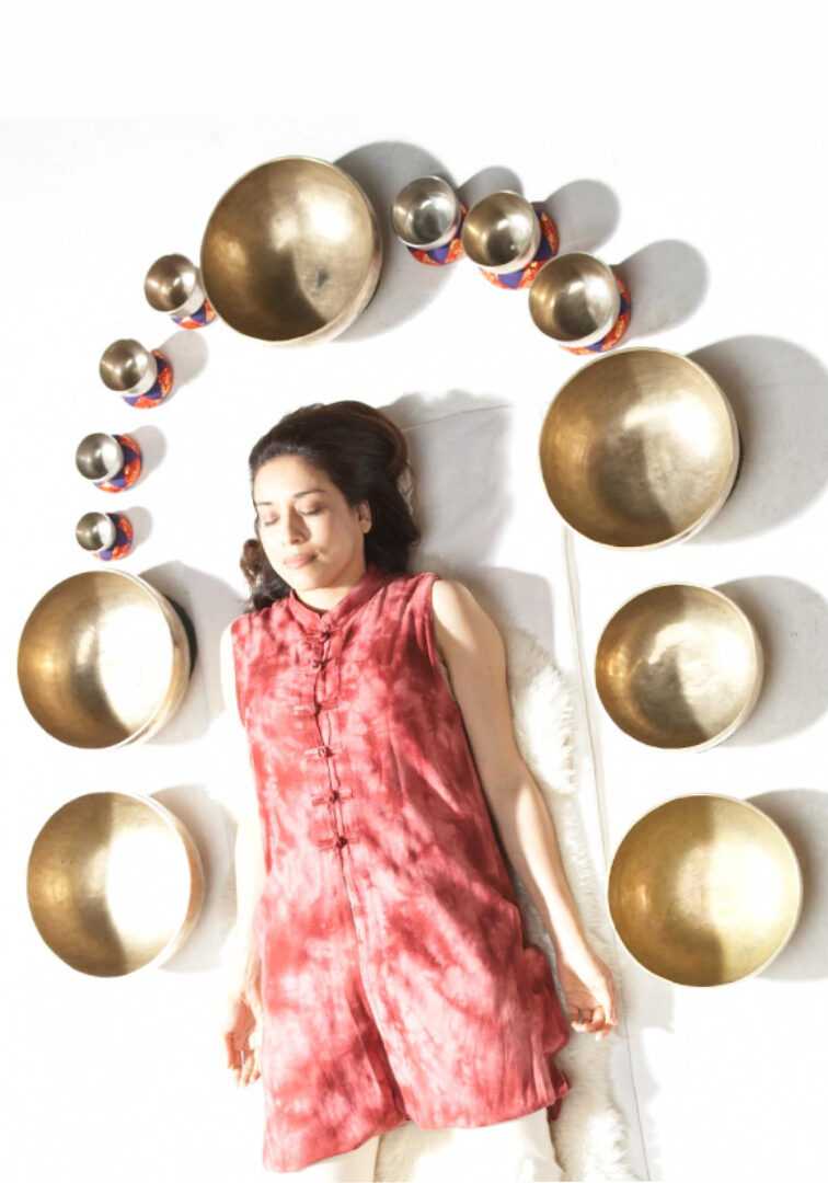 Woman meditating surrounded by singing bowls.